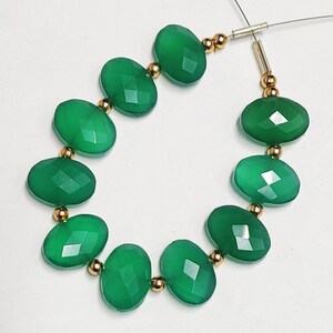 Puede incluir: Una hebra de cuentas de piedras preciosas verdes con separadores dorados. Las cuentas son de forma ovalada y tienen un acabado facetado.