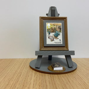 Adorno de sello de Peter Rabbit de Beatrix Potter. Sello postal enmarcado de Peter Rabbit, de 1979, con caballete gris, base y envoltorio de regalo. Incluye niños.