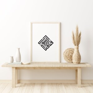 May include: A black and white calligraphy print in a square frame, hanging on a white wall above a light wood bench. The print is of Arabic script in a geometric design. There are two white vases and a woven basket on the bench.