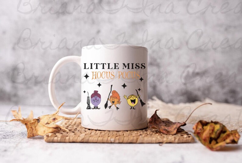 May include: White ceramic mug with a black and white design featuring the text "Little Miss Hocus Pocus" and three cartoon characters.