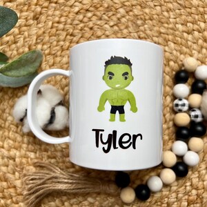 May include: White ceramic mug with a green cartoon character of the Hulk and the name "Tyler" printed on it.
