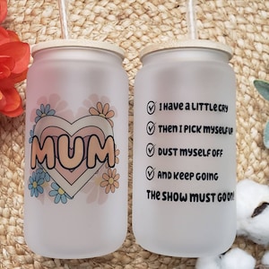 May include: Two frosted glass tumblers with bamboo lids and straws. One tumbler has a pink heart with the word "MUM" inside and floral designs. The other tumbler has a checklist with the text "I have a little cry, then I pick myself up, dust myself off, and keep going. The show must go on!"