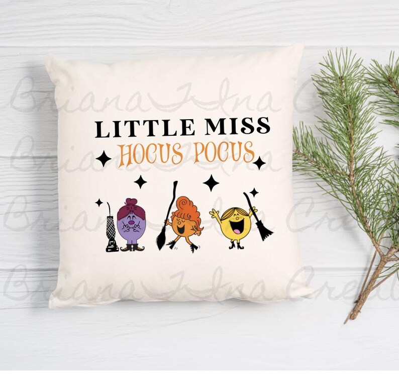 May include: A white pillow with the text "Little Miss Hocus Pocus" and three cartoon characters with broomsticks. The characters are purple, orange, and yellow.