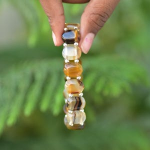 May include: A bracelet made of brown, white and black agate beads with silver spacers.