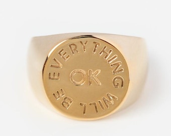 Puede incluir: Anillo de sello de oro con la inscripción "Everything will be ok" alrededor de un círculo con las letras "OK" en el centro.