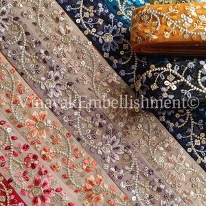 Puede incluir: Surtido de galones bordados con diseños florales en varios colores, incluyendo rojo, rosa, azul y dorado. El galón está hecho de una tela transparente con lentejuelas y cuentas. El galón está etiquetado como "Emb1414".