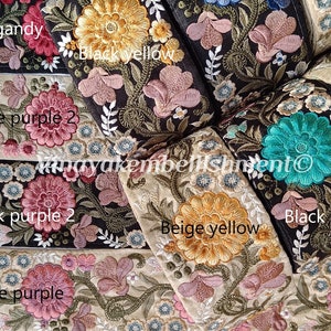 Peut inclure: Gros plan d'une garniture brodée avec différentes couleurs et motifs floraux. La garniture est disposée en plusieurs couches, mettant en valeur différentes couleurs et motifs. Les couleurs comprennent le beige, le noir, le vert, le bleu, le jaune et le violet. La garniture est étiquetée avec les noms des couleurs et le texte "Manayakembellishment".