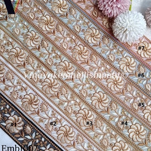 May include: Seven different trims of white embroidered lace with gold thread and sequins. The trims are arranged in a row, with the top trim being the widest and the bottom trim being the narrowest. Each trim has a different design, but all of them feature floral motifs. The trims are labeled with numbers 1 through 7.