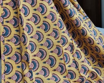 May include: Yellow fabric with a repeating pattern of blue, white, and red fan-shaped designs.