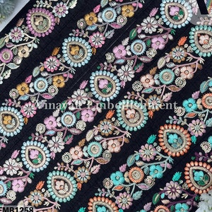 May include: Black fabric trim with a repeating pattern of colorful embroidered flowers and paisley shapes. The trim is decorated with sequins and beads. The trim is labeled "EMB1258".