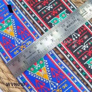 May include: Two colorful patterned fabric trims with a ruler measuring 15 inches. The trim is red, blue, green, yellow, and white. The trim is woven with a geometric pattern.