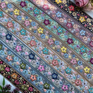 May include: Assortment of embroidered floral ribbons in various colors, including pink, blue, yellow, and purple. Each ribbon features detailed floral patterns and decorative stitching. The text "Emb1629" is visible at the bottom.