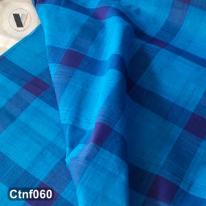 May include: Close-up of a blue fabric with a plaid pattern in shades of blue and purple. The fabric is folded, creating shadows and depth. The text "Ctnf060" is visible in the bottom left corner.