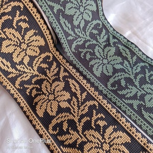May include: Two black and gold embroidered trim ribbons with a floral pattern. The ribbon on the left has gold thread embroidery and the ribbon on the right has green thread embroidery.