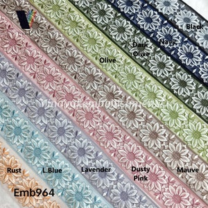 May include: A close-up of ten different colored embroidered trims with a sunflower design. The colors are rust, light blue, lavender, dusty pink, mauve, olive, dark olive, navy, and black. The trim is labeled "Emb964".