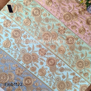 May include: Five strips of embroidered trim in various pastel colors, including light blue, pink, and gray. The trim features a floral design with gold thread embroidery. The trim is labeled "Emb1122".