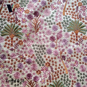 May include: A beige fabric with an embroidered floral pattern. The design features pink, purple, and green flowers, along with palm trees. The fabric has the text "Embf038" in the bottom left corner.