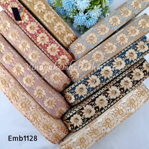 May include: Assortment of six embroidered trim ribbons with floral designs. The ribbons are in various colours, including gold, blue, black, white, pink, and red. The trim is embellished with gold thread. The text "Emb1128" is visible in the image.