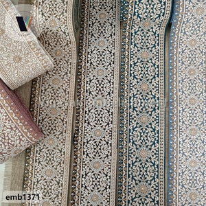 May include: Four different trims of embroidered fabric with a white floral pattern on a beige, brown, teal, and blue background. The trims are all approximately 1 inch wide and have a gold thread running through them. The trims are labeled "emb1371".