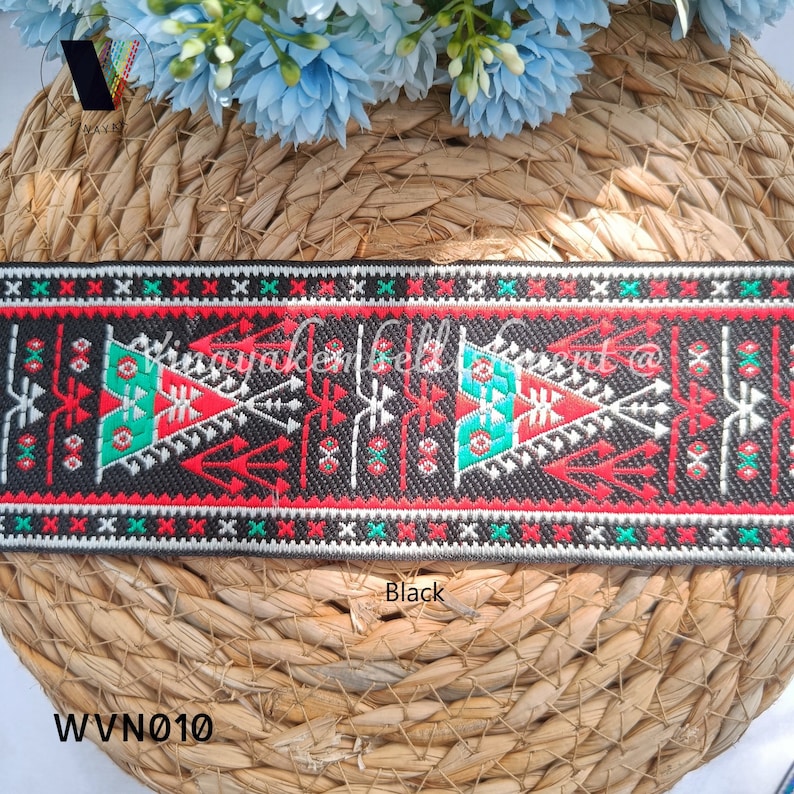 May include: Black and white woven trim with red and green geometric patterns. The trim has a repeating pattern of triangles and lines. The trim is labeled "Black" and "WVN010".