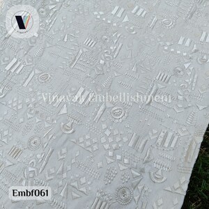 May include: White fabric with a geometric pattern embroidered in white thread. The fabric has a subtle texture and the embroidery is detailed and intricate. The fabric is called "Embf061".