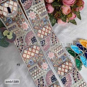 May include: Two pieces of gray embroidered trim with a geometric pattern in shades of pink, blue, and brown. The trim is made of a sheer fabric and has a delicate, feminine look. #5 emb1389