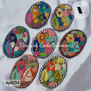 May include: Seven colorful oval-shaped embroidered patches with a black border. The patches feature a variety of abstract floral designs in shades of pink, blue, green, yellow, and orange.