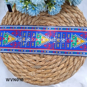 May include: Blue and white trim with a geometric pattern featuring red, yellow, and green accents. The trim is woven and has a textured surface. The trim is labeled "Blue" and "WVN010".