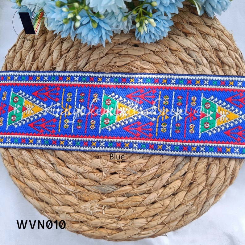 May include: Blue and white trim with a geometric pattern featuring red, yellow, and green accents. The trim is woven and has a textured surface. The trim is labeled "Blue" and "WVN010".