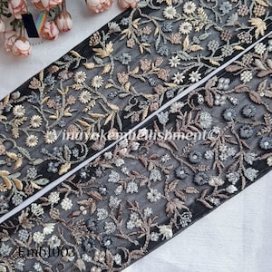 May include: Black mesh fabric trim with embroidered floral designs in silver, gold, and brown. The trim is approximately 2.5 inches wide and features a repeating pattern of flowers and leaves. The trim is labeled "Emb1003".