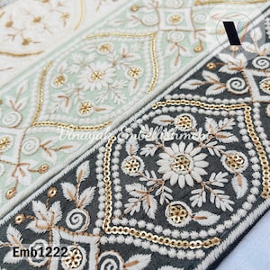 May include: Close-up of a black and white embroidered trim with gold sequins. The trim features a floral design with a repeating pattern. The text "Emb1222" is visible in the lower left corner of the image.