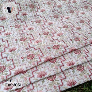 May include: A close-up of a white fabric with a repeating pattern of pink and red flowers in a geometric design. The fabric is folded in thirds, and the text "#4 Embf061" is visible in the lower left corner.