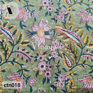 Puede incluir: Tela verde con estampado floral con flores rosas, blancas y amarillas. La tela tiene un diseño tradicional indio.