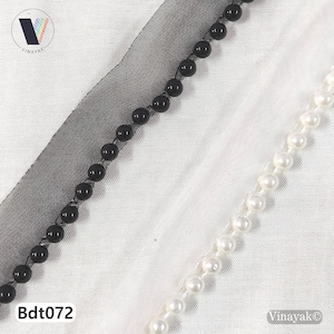 May include: Image of two beaded trims. One trim has black beads, and the other has white pearl-like beads. The trims are set against a white fabric background with a sheer black fabric overlay. The text "Bdt072" is visible.