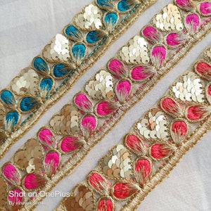 May include: Three rows of gold trim lace with sequins and colorful embroidered flower shapes. The top row is teal blue, the middle row is pink, and the bottom row is red.