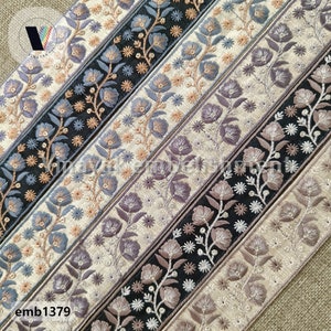 May include: Five different embroidered trim ribbons with floral patterns in shades of brown, black, gray, and blue. The ribbons are arranged in a diagonal pattern on a beige background. The text "emb1379" is visible in the lower left corner of the image.