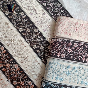 Könnte beinhalten: Nahaufnahme von vier verschiedenen bestickten Borten mit Blumendesigns. Die Borten sind in den Farben Rosa, Blau und Braun gehalten und alle auf schwarzem Hintergrund.