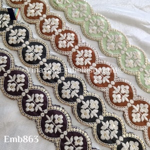 May include: Four different trims of embroidered lace with scalloped edges. The trims are in brown, black, dark brown, and green. The embroidery is white and features a floral design. The trims are all approximately 1 inch wide.