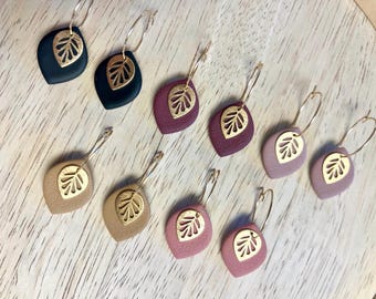 May include: Ten hoop earrings arranged in pairs, each featuring a matte, teardrop-shaped charm in various colors including black, deep plum, tan, dusty rose, and mauve. Each charm is accented with a small, gold-toned, cut-out leaf pendant.