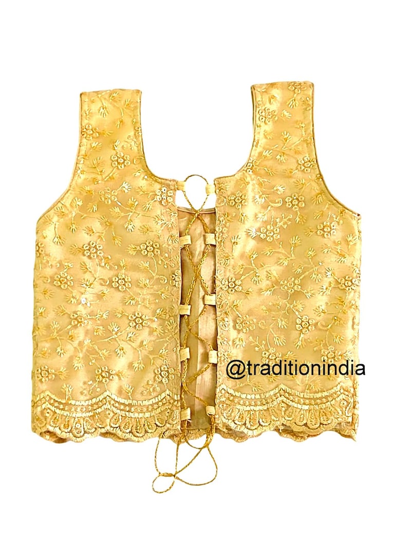 May include: A gold embroidered sleeveless blouse with a lace trim and a lace-up back. The blouse is decorated with floral patterns and sequins. The text "@traditionindia" is visible on the bottom right corner of the blouse.