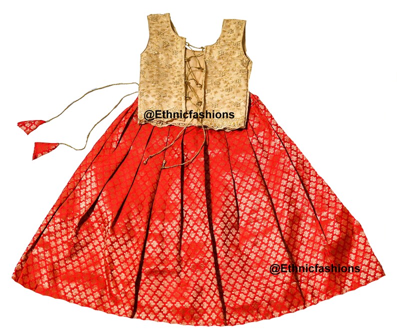 May include: A red and gold sleeveless dress with a lace-up bodice and a full skirt. The skirt has a floral pattern and the bodice is embroidered. The dress is perfect for a special occasion.
