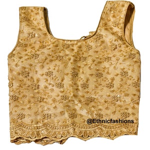 May include: A gold sleeveless blouse with a floral embroidered design and a scalloped hem. The blouse has a scoop neckline and a back zipper closure. @Ethnicfashions