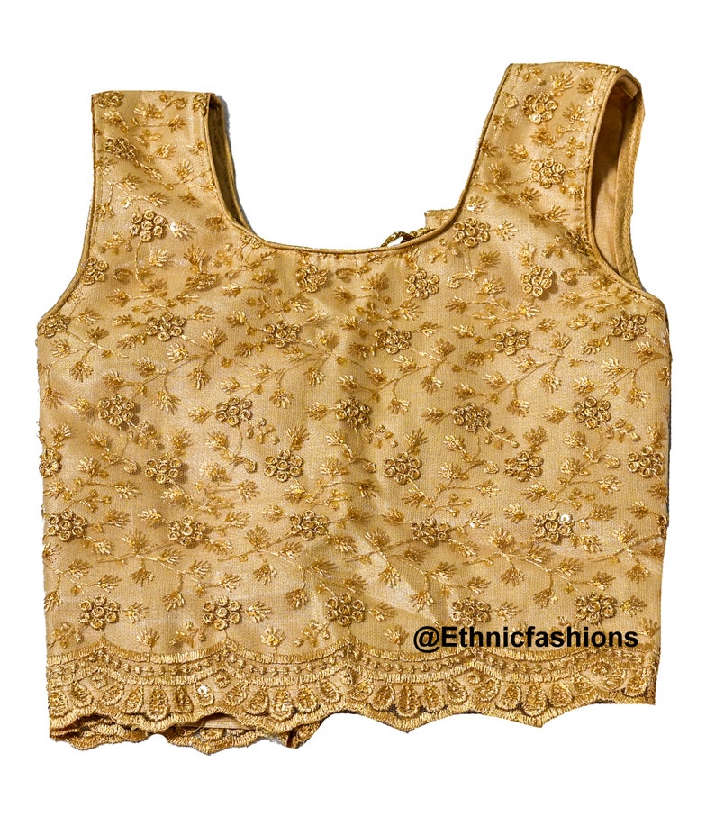 May include: A gold sleeveless blouse with a floral embroidered design and a scalloped hem. The blouse has a scoop neckline and a back zipper closure. @Ethnicfashions