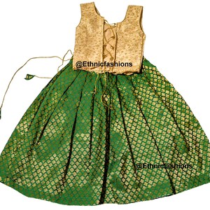 May include: A green and gold sleeveless dress with a gold embroidered bodice and a green skirt with a gold pattern. The dress has a lace-up back and a gold tassel on the skirt.