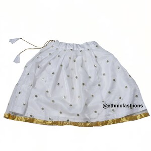 May include: White skirt with gold trim and sequins. The skirt has a drawstring waist and is made of a sheer fabric. @ethnicfashions