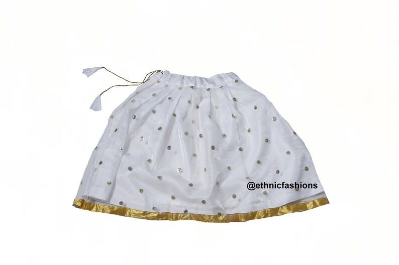 May include: White skirt with gold trim and sequins. The skirt has a drawstring waist and is made of a sheer fabric. @ethnicfashions