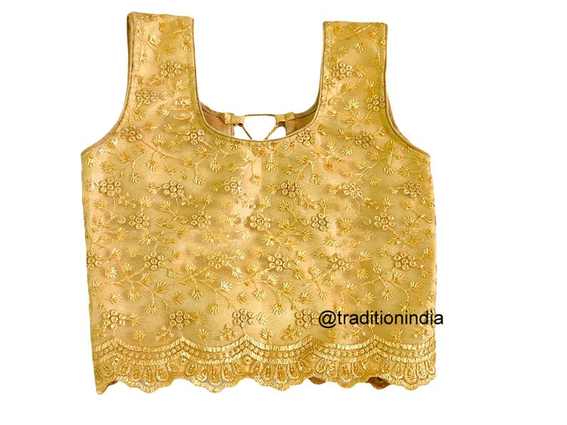 May include: A gold embroidered sleeveless blouse with a scalloped hem. The blouse features a floral pattern and a tie-back detail.