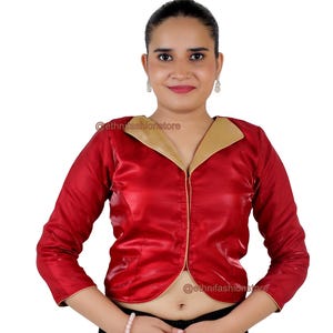 May include: A red satin blouse with a gold collar and long sleeves. The blouse has a zip fastening at the front and a cropped hemline.