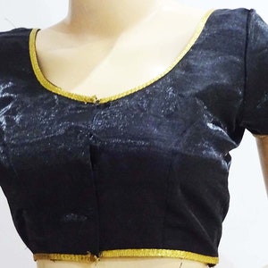 May include: Black satin blouse with gold trim around the neckline and sleeves. The blouse has a button closure at the front.