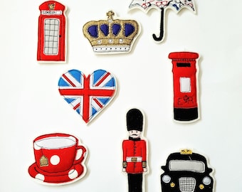 May include: A collection of fabric appliqués featuring iconic British symbols. Includes a red telephone booth, a gold crown with blue accents, a Union Jack heart, a red postbox, a black taxi, a red teacup, a soldier, and a patterned umbrella.
